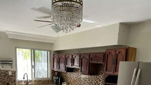 Una cocina con armarios de madera oscura, un refrigerador de acero inoxidable, una estufa a gas y una araña.