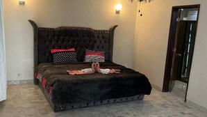 Un dormitorio con cabecera capitonada, ventilador de techo y piso de baldosas de piedra.