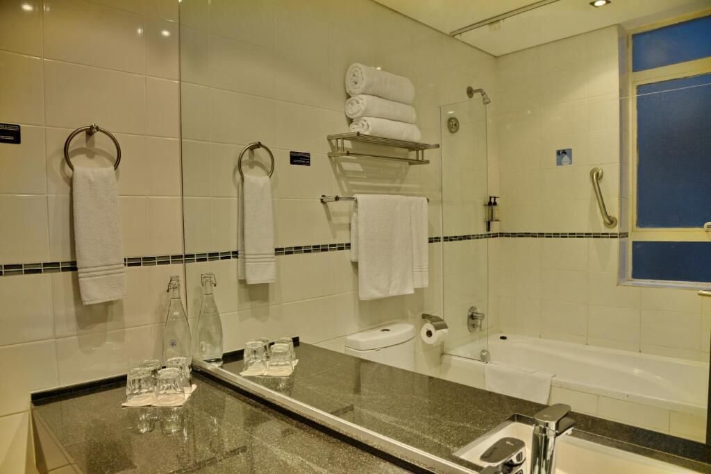 A bathroom with a sink, mirror, towel rack, and a shower area.