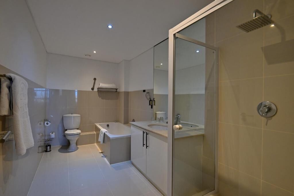 Een moderne badkamer met toilet, bad en douche.