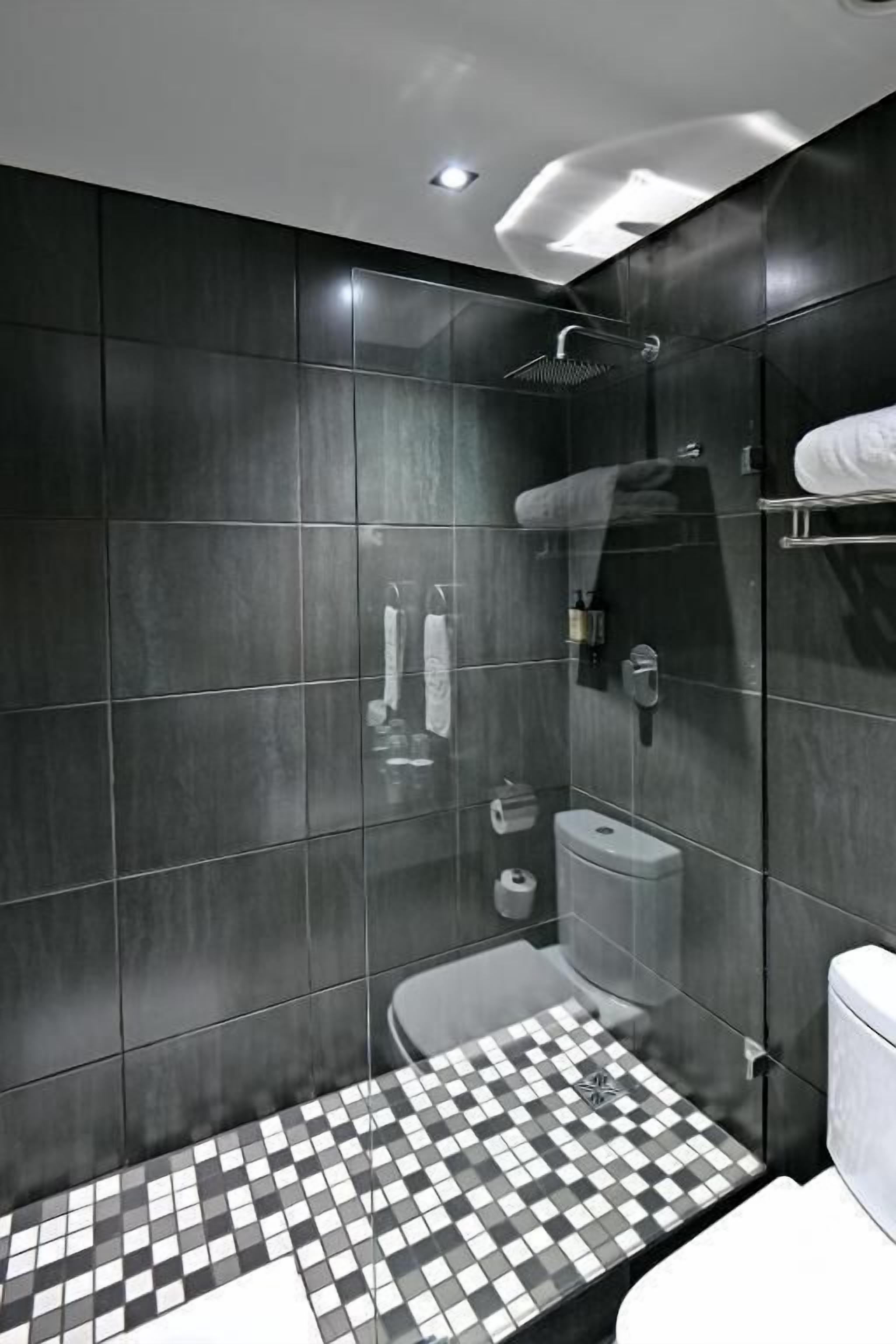 A modern bathroom with a checkered floor, a glass-enclosed shower, and a toilet.