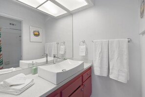 Moderni kylpyhuone, jossa on suuri peili, kaksi pesuallasta ja suihku.