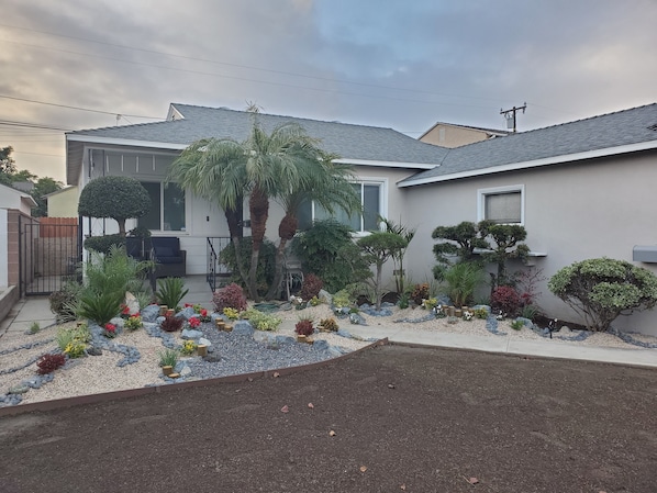 Une maison d’habitation dotée d’un jardin bien entretenu, agrémenté de diverses plantes et d’un petit espace patio.