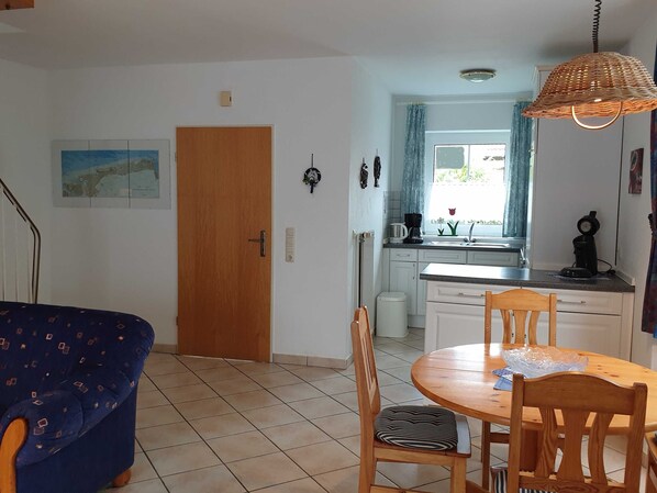 A compact kitchen with a dining area, a wooden door, and a map on the wall.