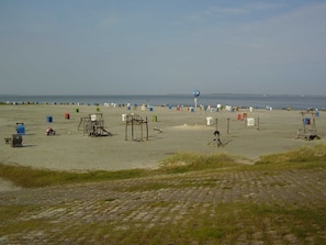 Une plage parsemée de nombreuses cabanes de plage colorées et surmontée d’une grande structure sphérique bleue.