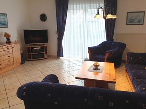 A living room with a TV, two patterned sofas, a wooden coffee table, and a cabinet.