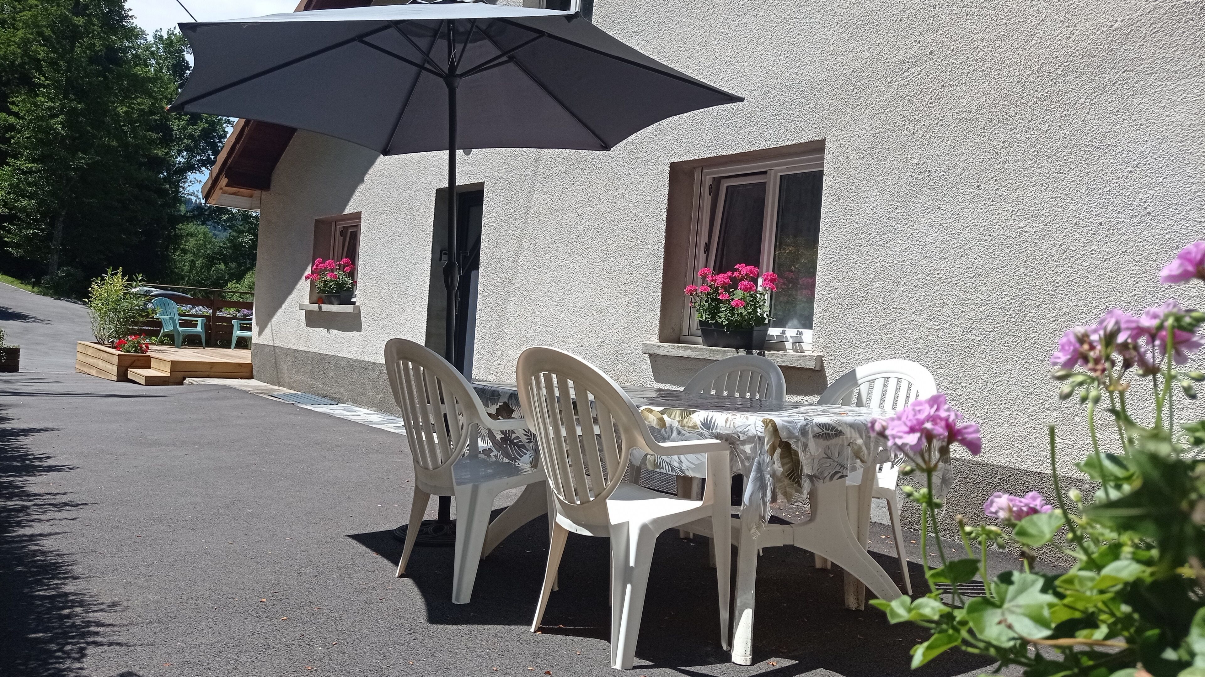 An outdoor seating area with a table and chairs, a large umbrella, and potted plants.