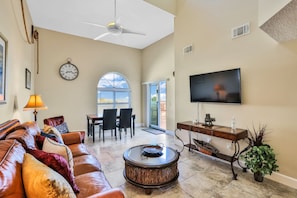 Relax in this stylish living room with a high ceiling, comfortable sofa, and large window offering a view of the outdoors.