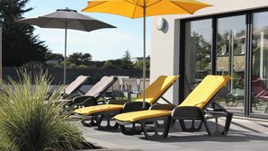 Outdoor lounge chairs with yellow cushions, a glass building, and a yellow umbrella. - House with 30°C pool and enclosed garden 300m from Les Amiets beach - Bretagne (Cléder)