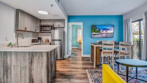 A modern kitchen with grey cabinets, a stainless steel refrigerator, and a wooden island. - Stylish Condo CDC Standards Private Balcony 2BD 2BA 6en165 (Orlando)