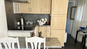 Eine Küche mit Holzschränken, einer Edelstahl-Dunstabzugshaube, einem Esstisch mit zwei Stühlen und einer Topfpflanzen-Orchidee.