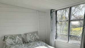 Ein Schlafzimmer mit Bett, weißen Wänden und einem Fenster mit Vorhängen.