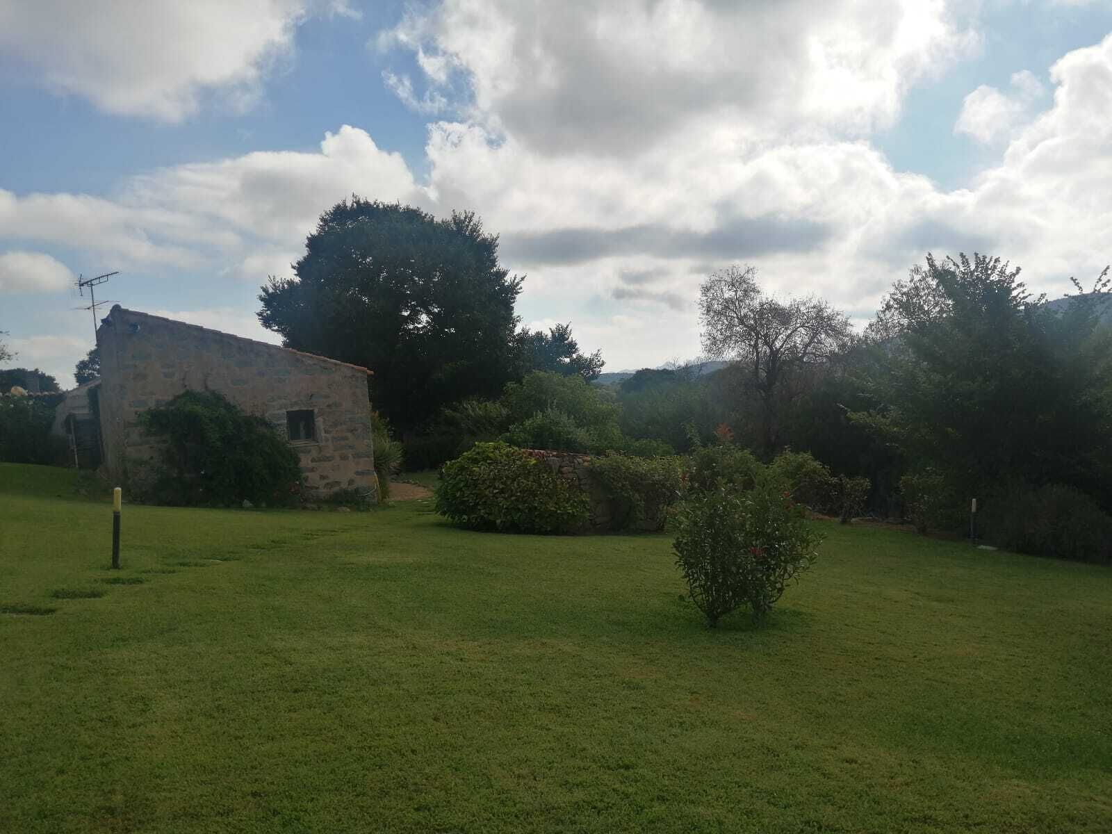 A stone building with a sloped roof, surrounded by a grassy field and trees.