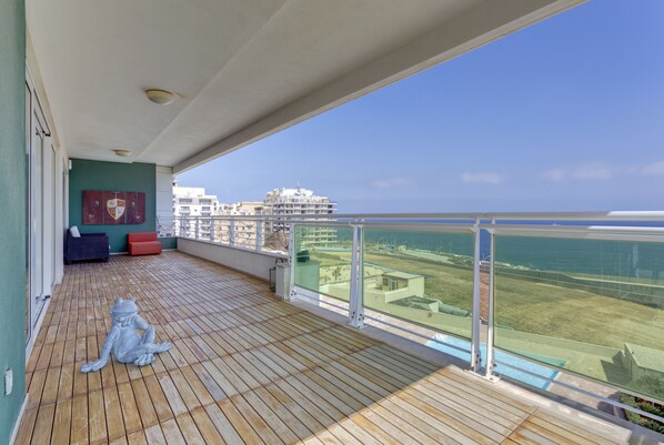 A balcony with a view of the sea, a wooden floor, and a statue of a cat. - Seafront Apartment in Sliema With Pool, Upmarket Complex (Sliema)