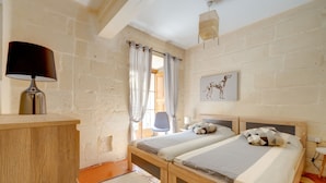 Een slaapkamer met twee bedden, een bureau, een stoel, een lamp en een foto aan de muur.