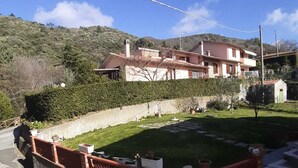 Zona residencial con una casa de dos pisos, un camino pavimentado y un coche blanco estacionado al frente.