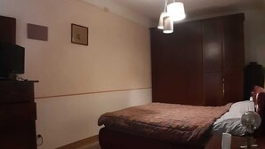 Un dormitorio con cama, cómoda, armario y una lámpara en el techo.