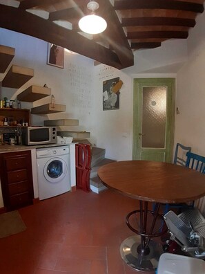 Compact kitchen area with a washing machine, microwave, and dining table.