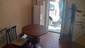 Un pequeño comedor con una mesa redonda y sillas, un refrigerador y una puerta que da al exterior.