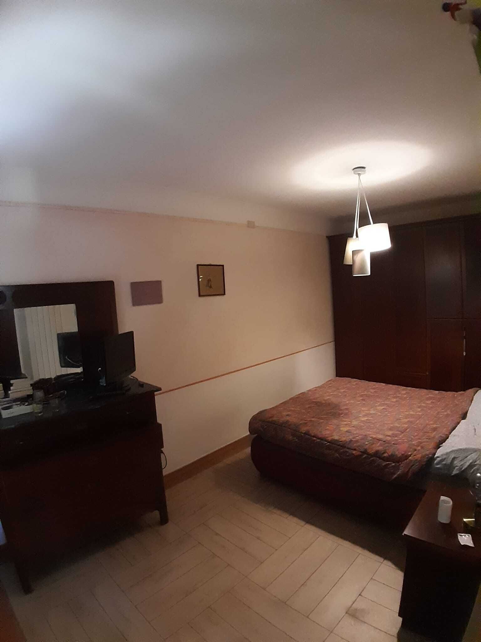 A bedroom with a bed, a desk with a computer, and a wardrobe.