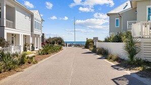 Una carretera costera bordeada por casas de dos pisos con balcones, que conduce hacia el mar.