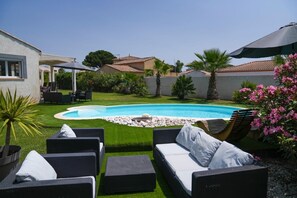 Un jardin avec une piscine, entouré de meubles d’extérieur et de verdure.
