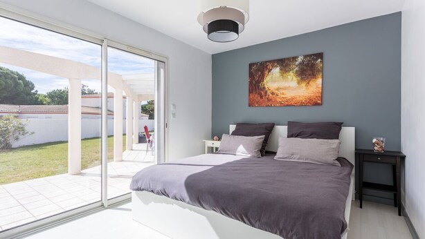 A modern bedroom with a large bed, a painting, and a view through a glass door to an outdoor area. - Magnificent property - 1000m² - Private Pool (Agde)