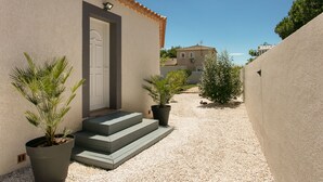 A building with a beige exterior, a tiled roof, and a door. There are steps leading to the door, and two potted plants on either side. - Magnificent property - 1000m² - Private Pool (Agde)