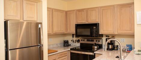 A modern kitchen with stainless steel appliances, wooden cabinets, and a granite countertop.