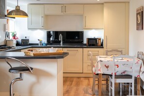 A modern kitchen with a central island, a dining area with a table and chairs, and a microwave on the countertop.
