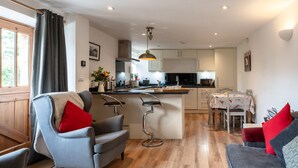A modern kitchen with a central island, bar stools, and a dining area with a table and chairs.