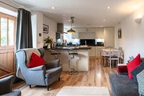 A modern kitchen with a central island, bar stools, and a dining area with a table and chairs.