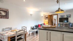 A modern kitchen with a dining area, a TV, and a coffee-themed poster.