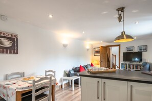 A modern kitchen with a dining area, a TV, and a coffee-themed poster.