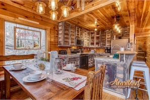 Cozy cabin interior with a central island kitchen, wooden cabinets, and a dining table.