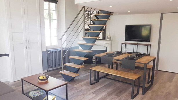 Un espace de vie moderne comprenant un escalier en colimaçon, un coin repas et un téléviseur.
