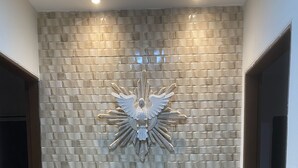 A hallway with a textured wall and a decorative emblem. - Casa de Praia Condomínio Fechado em Ipioca (Maceió)