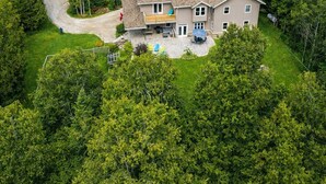 A two-story house with a large front yard and a driveway leading to a garage. - Bruce “GOLF” Getaways (Lion's Head)