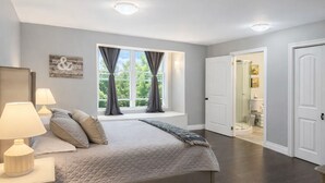 A bedroom with a bed, bedside lamps, a window with curtains, a door, and a small bench by the window. - Bruce “GOLF” Getaways (Lion's Head)
