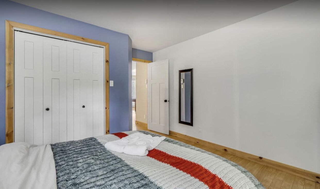 A bedroom with a bed, a large window, and a door.