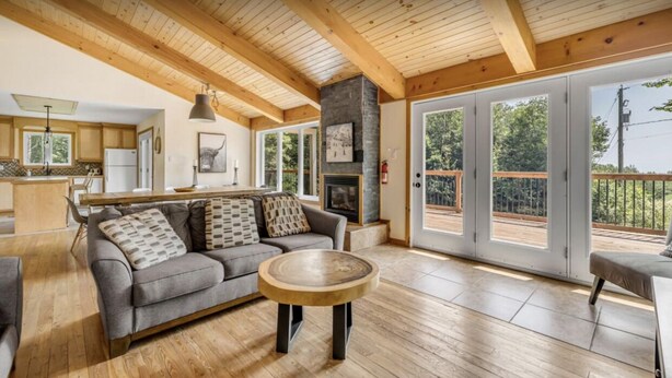 Un salon spacieux avec un canapé gris, une table basse en bois et une cheminée.