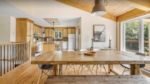 Une cuisine spacieuse avec des meubles en bois, une grande table à manger et une vue sur l’extérieur.