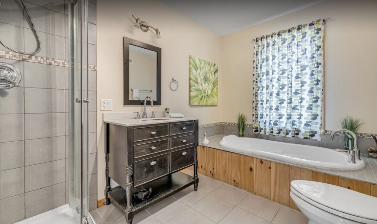 Une salle de bain avec une douche, un meuble-lavabo avec des tiroirs, une grande baignoire et des toilettes.