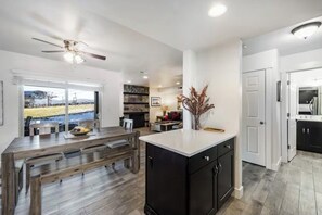 A modern kitchen with a central island, dark cabinetry, and a view of a construction site outside. - Lift in Backyard! Park City Gem - Renovated! (Park City)
