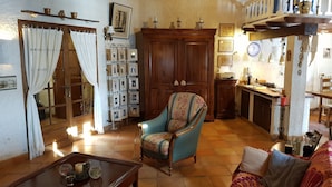 A cozy living room with a wooden cabinet, a patterned armchair, a sofa, and a coffee table. - Totally private 8 adults plus 2 children luxe villa with heated swimming pool (Régusse)