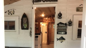A cabin interior with a wooden ceiling, a couch with a blue cushion, and a sign reading "The Cabin". - 1-bedroom cabin near Huron-Manistee National Forest (Newaygo)