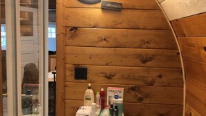 A small room with wooden walls, a round skylight, a white cabinet with toiletries, and a large heater. - 1-bedroom cabin near Huron-Manistee National Forest (Newaygo)