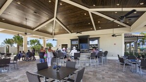 An outdoor patio area with tables and chairs, a bar, and a ceiling fan. - Lakewood National Golf and Resort,  3 Bed Condo -Unlimited Golf! (Lakewood Ranch)