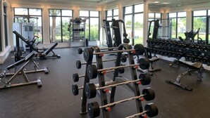A spacious gym with various weightlifting equipment, large windows, and a clean, modern design. - Lakewood National Golf and Resort,  3 Bed Condo -Unlimited Golf! (Lakewood Ranch)