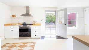 A modern kitchen with white cabinetry, a stainless steel range, and a large window. - Renovated Catskills Farmhouse - hiking, swimming, quaint towns, 1st floor living (Denver)